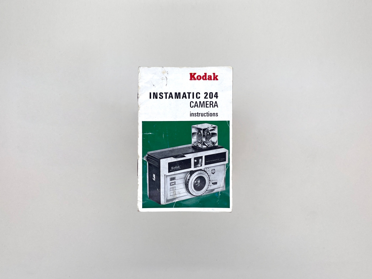 Cover of a small instruction manual for a Kodak Instamatic 204 camera featuring a photo of the camera with a flashcube attached.
