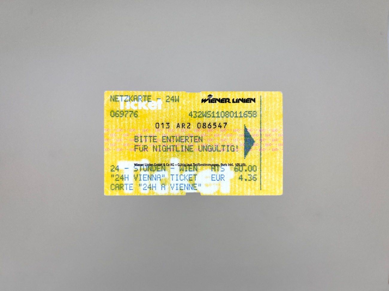 A yellow ticket with green and black writing and white and pink graphic details overlayed and interrupting each other.