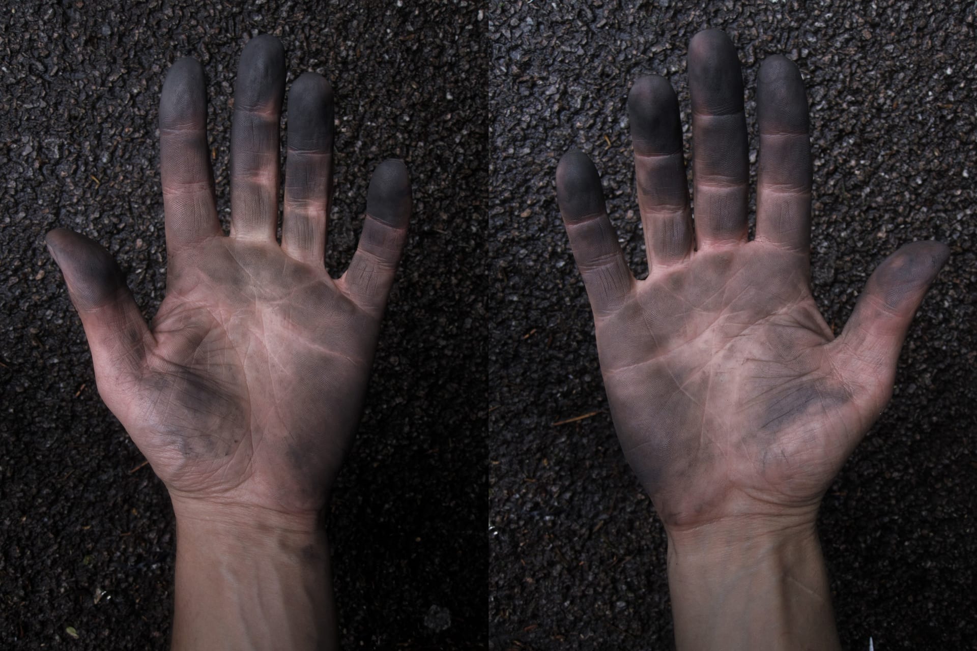 Two caucasian hands held out  against an asphalt background, and covered in chain oil and tyre dirt after fixing a puncture. 
